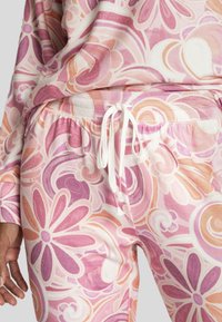 Roze lounge set met een bloemachtige zwirlpatroon. De stof is zacht met een ontspannen pasvorm, een elastische tailleband en een witte trekkoord.