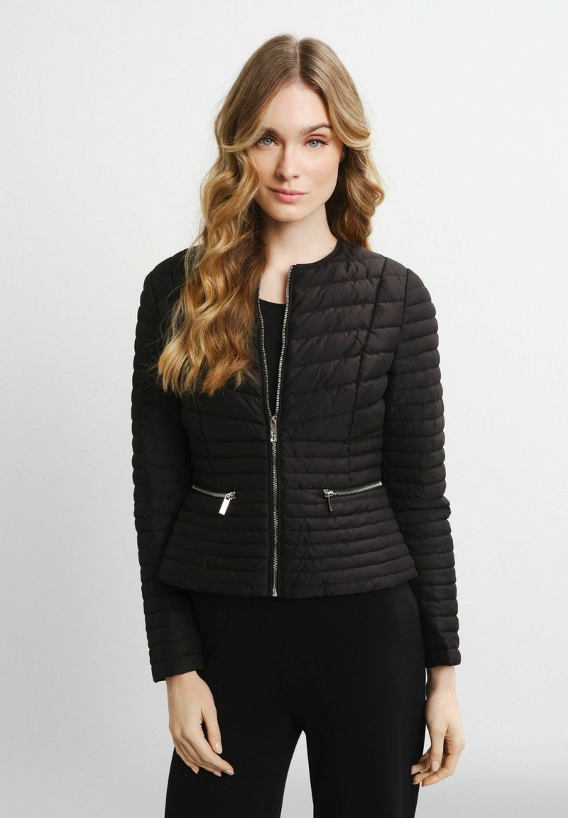 Schwarze gesteppte Jacke mit tailliertem Schnitt, rundem Ausschnitt und Reißverschluss-Taschen mit metallischen Akzenten. Glatte Textur.