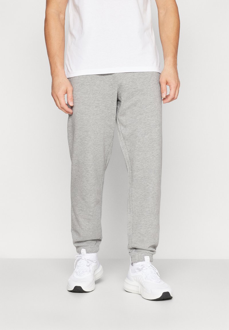 Grijze katoenen joggerpants met een elastische tailleband en enkelmanchetten, gecombineerd met witte sport sneakers. Eenvoudig ontwerp, relaxte pasvorm.