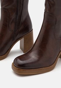 Ruske nahkasaapad ankle, smooti viimistlusega, puidust plokknõlv, külgzipper ja ümar varvas. Pehme tekstuur nahapinnal.