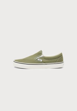 Πάνινο παπούτσι Vans slip-on σε ελιά, με λευκή λαστιχένια σόλα και μαύρη ρίγα, με ελαστικά πλαϊνά πάνελ και ορατή ετικέτα με το λογότυπο.