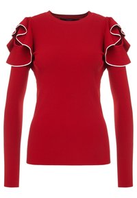 Maglietta rossa a maniche lunghe con texture a costine, caratterizzata da appoggi a volant sulle spalle con un bordo bianco. Collo a giro.