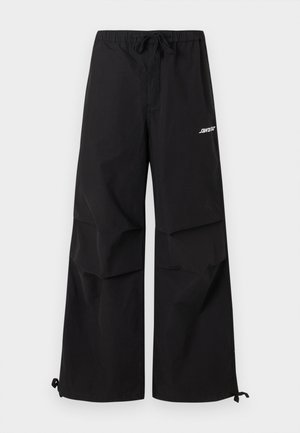 Čierne široké nohavice s elastickým pásom, sťahovacou šnúrkou na koncoch nohavíc a bielym logom na hornom stehne.