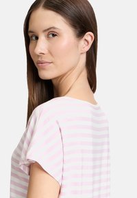 T-shirt à manches courtes avec des rayures horizontales roses et blanches, présentant un col rond et une texture de tissu douce.