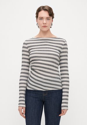 Pruhovaný dlouhý rukáv top v černé a krémové barvě, s lodní výstřihem a žebrovanou texturou, spárovaný s tmavými džíny.