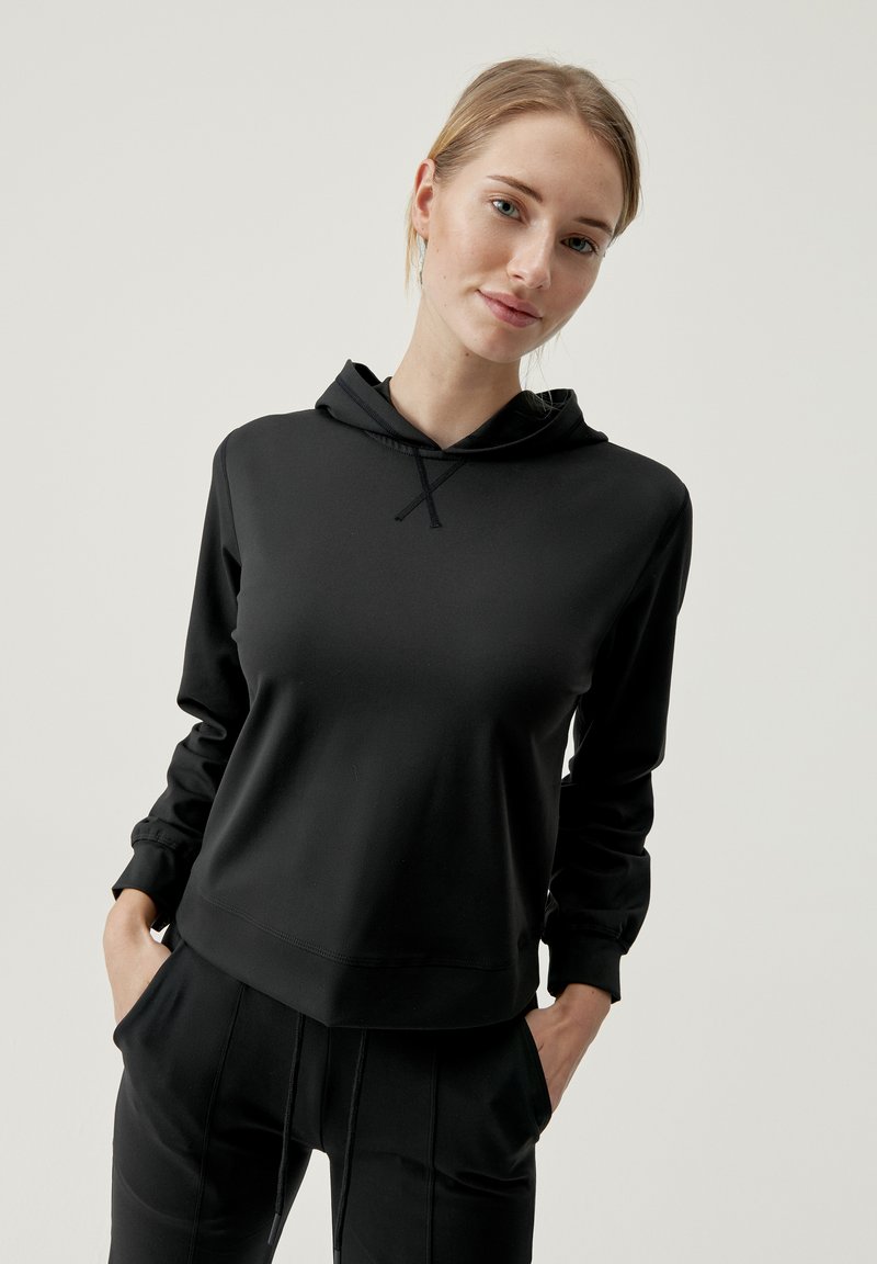Felpa nera con un fit rilassato, realizzata in un tessuto morbido. Presenta un cappuccio regolabile e maniche lunghe con polsini a coste.