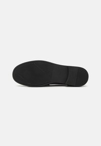Talpa de pantof din cauciuc negru, cu un model texturat pentru aderență, având o margine netedă și un toc ușor. Design minim, fără elemente decorative suplimentare.