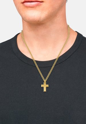 Goldfarbene Kettenhalskette mit einem minimalistischen Kreuzanhänger; getragen über einem schwarzen Rundhalsausschnitt-Shirt. Einfaches und modernes Design.