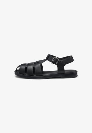 Black leather men's sandal with closed toe straps, side buckle, and flat sole, shown in profile on white background.