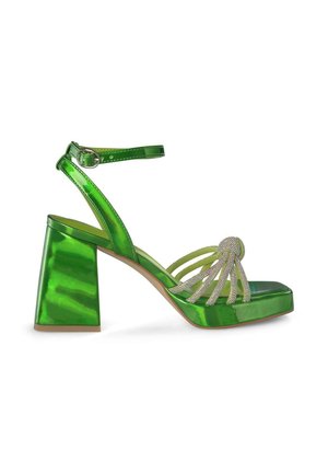 Sandale à talon carré en cuir verni vert avec une sangle, détail de perles décoratives sur la partie supérieure et finition brillante.