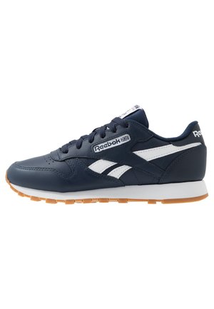 Navy blue Reebok sneaker with white side stripes, white midsole, gum rubber outsole, and black laces, shown from the outer side.