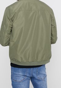 Olivegrüner Bomberjacke mit glatter Textur, gerippten Bündchen und Saum, mit einem schlichten Design ohne Verzierungen.