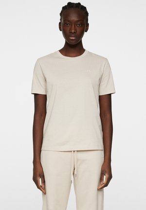 Beige katoenen t-shirt met een ronde hals, korte mouwen en een subtiel logo op de borst. De stof lijkt glad en lichtgewicht te zijn.