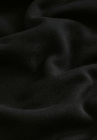 Black fabric with a smooth texture, displaying gentle waves and folds, highlighting its softness and suitability for various applications.