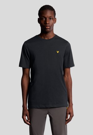 Schwarzes T-Shirt mit kurzen Ärmeln aus weicher Baumwolle, mit einem Rundhalsausschnitt und einem kleinen gelben Logo auf der linken Brust.