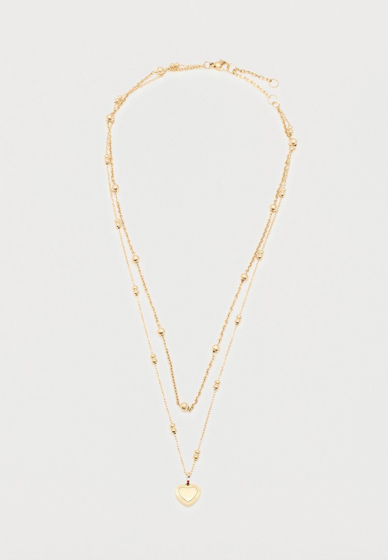 Κολιέ διπλής στρώσης με αλυσίδα από χρυσό, μικρές σφαιρικές χάντρες και μενταγιόν σε σχήμα καρδιάς στην κάτω αλυσίδα.