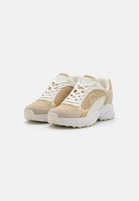 Sko med en beige og gull mesh-overdel, semsket detaljer, hvit polstret såle og kontrasterende snørebånd. Rund logo på siden.