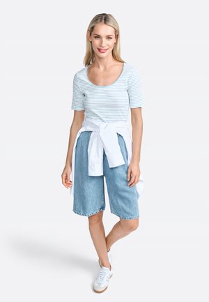 Light blue striped short-sleeve top paired with denim shorts and white sneakers, accented by a tied white shirt at the waist.