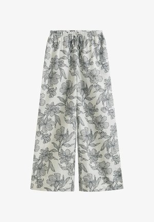 Witte broek met wijde pijpen, versierd met zwarte bloemenlijnen en een elastische tailleband met trekkoord.