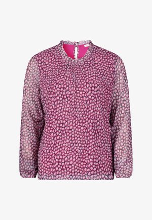 Paars geprinte blouse met lange mouwen en geplooide halslijn, gecombineerd met marineblauwe hoge taille broeken en witte puntige hakken.