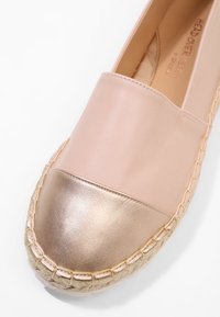 Espadrille slip-on avec dessus en cuir rose blush et bout métallique doré, avec une couture de semelle enveloppée de corde.