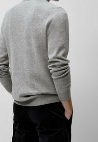 Szary sweter dziany z okrągłym dekoltem, ściągaczami na mankietach i na dole. Materiał jest miękki i teksturowany, noszony na ciemnych spodniach.