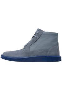 Stivaletti in suede grigi con una suola in gomma blu, dotati di un design con lacci piatto e un pannello in tessuto morbido sulla parte superiore.