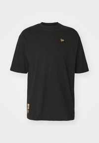 T-shirt corto a maniche corte in cotone nero con scollo tondo. Presenta un piccolo logo dorato sulla parte superiore sinistra e un'etichetta dorata sul bordo.