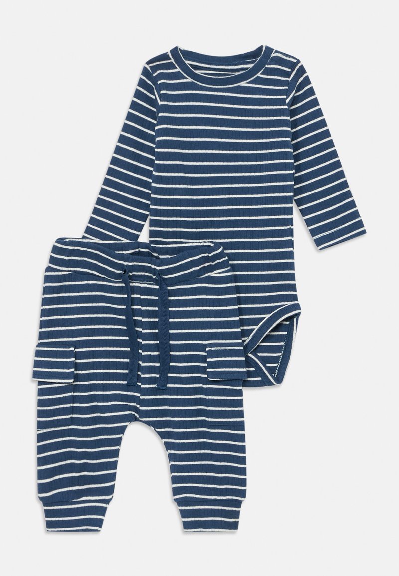 Gestreiftes Baby-Outfit mit einem langärmeligen Body und passenden Hosen. Hergestellt aus weichigem Baumwollstoff in Marineblau mit weißen Streifen, inklusive Kordelzug und Taschen.