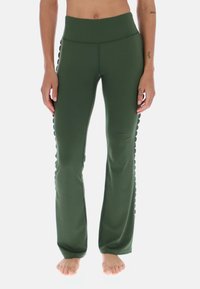 Zielone legginsy do jogi z wysokim stanem, wykonane z elastycznego materiału. Posiadają falbaniasty detal po bokach. Dopasowany krój, rozszerzające się na dole.