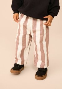 Gestreepte broek in zacht beige en lichtroze stof, met een ontspannen pasvorm en elastische tailleband, gecombineerd met zwarte instapschoenen.