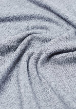 Tissu tricoté gris clair doux avec des plis légers et une texture lisse montré en gros plan.