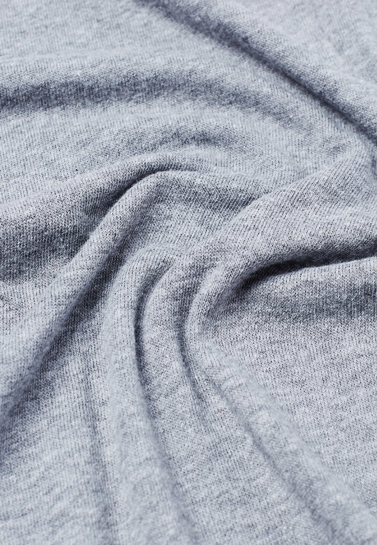 Tissu tricoté gris clair doux avec des plis légers et une texture lisse montré en gros plan.