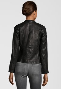 Schwarze Lederjacke mit tailliertem Schnitt, glatter Textur und langen Ärmeln. Verfügt über Steppdetails und einen hohen Kragen hinten.