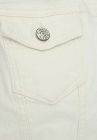 White denim shirt pocket with silver snap button. Features diagonal stitching and a textured surface, emphasizing the material's durability.