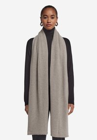 Lys grå tørklæde lavet af blødt stof, med et enkelt design, glat tekstur og færdige kanter, der hænger elegant omkring halsen.