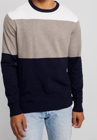 Herren Strickpullover mit horizontalen Streifen in Weiß, Hellgrau und Marineblau. Gerippte Bündchen und Saum. Weiche Textur, Rundhalsausschnitt.