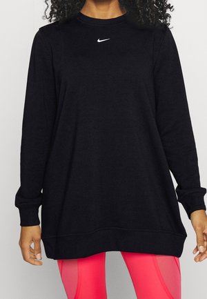 Sweatshirt noir oversize avec des manches longues, des poignets côtelés et un logo Nike blanc sur la poitrine, associé à des leggings roses.