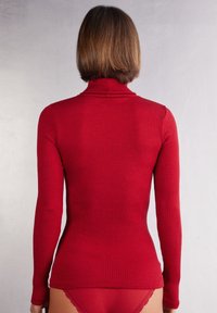 Červený žebrovaný top s dlouhým rukávem a rolákem, se slim fit siluetou, vyrobený z měkké tkaniny, s texturovanými žebry po celé ploše oděvu.