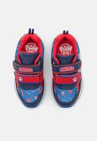 Sinine ja punane laste spordijalatsite mudel võrkmaterjalist, millel on tallamuster käpa jälgedega, Velcro rihmad ja "PAW Patrol" logo.