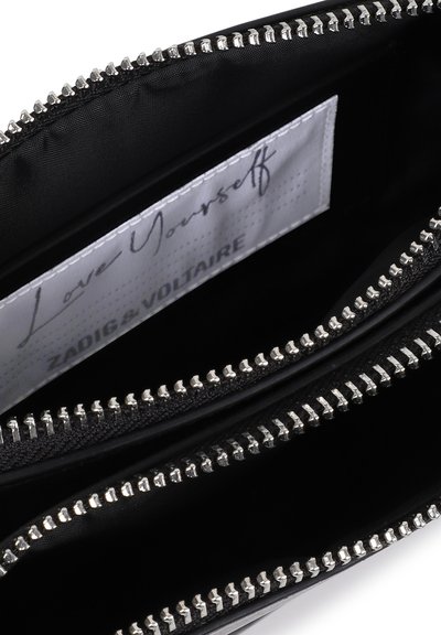 Μαύρο τσαντάκι με φερμουάρ σε ασημένιο χρώμα, ανοιχτό ώστε να φαίνεται η εσωτερική ετικέτα υφάσματος που γράφει "Love Yourself" και το εμπορικό όνομα Zadig & Voltaire.