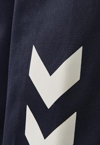 Granatowy materiał o teksturowanym wykończeniu, z dużym białym wzorem w zygzak. Elementy wzornicze tworzą kontrastowy i dynamiczny wygląd.