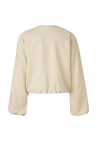 Krótką kremową bluzkę z długimi, bufiastymi rękawami i zaokrąglonym tylnym brzegiem. Gładka faktura z subtelnymi przeszyciami na ramionach.