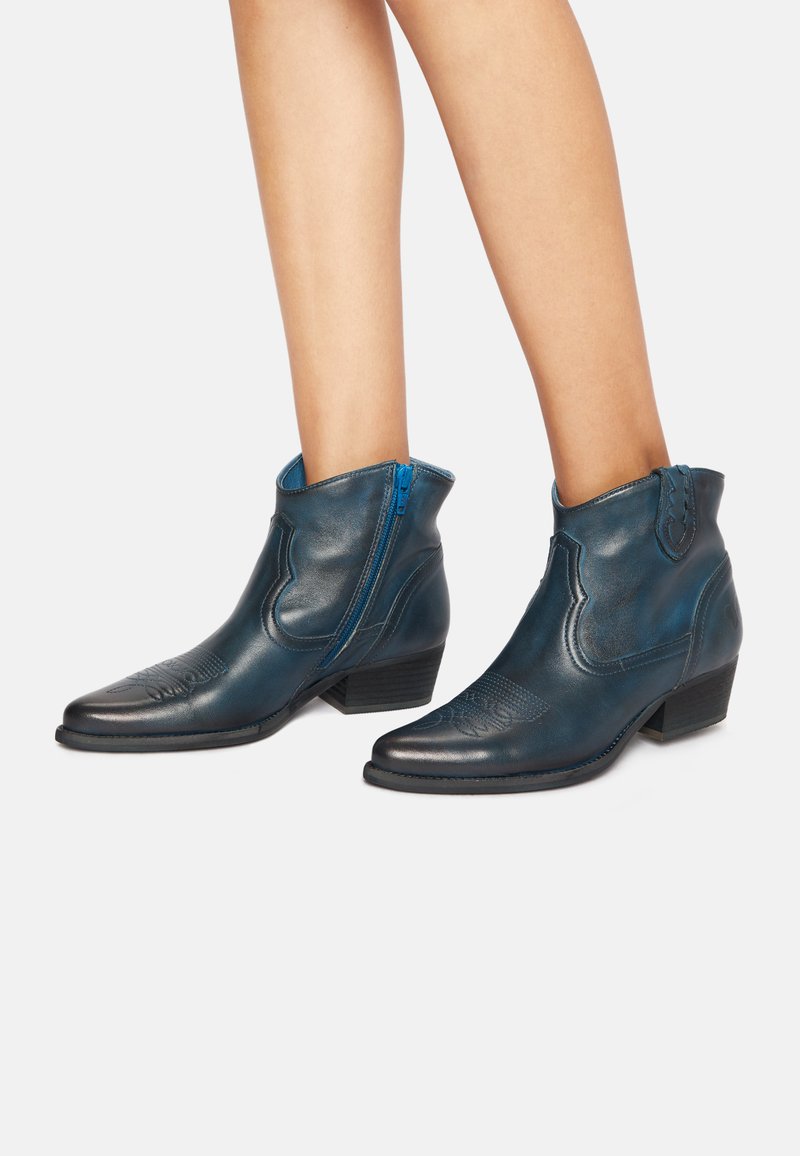 Botas de tobillo de cuero azul con punta afilada, detalles texturizados y cremallera lateral, con un tacón pequeño y costuras decorativas.