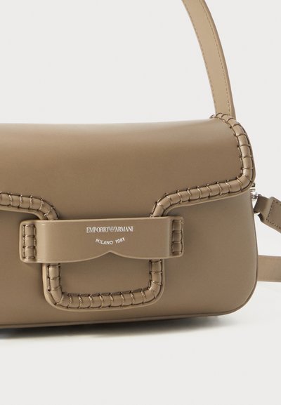 Brown faux leather shoulder bag with a woven edge, magnetic closure, and silver logo detail. Compact rectangular shape with an adjustable strap.