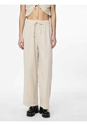 Pantalones beige de pierna ancha con cintura elástica y cordón, fabricados en tejido texturizado, combinados con zapatos negros de tacón grueso.