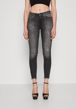Sorte denim skinny jeans med slidte detaljer og frynset kant, parret med sorte platform sandaler og en cropped top.