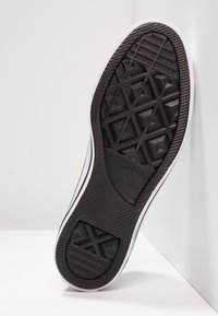 Suola di scarpa in gomma nera con un motivo geometrico, design flat, e bordo laterale bianco. Logo visibile vicino al tallone, che offre grip e durabilità.