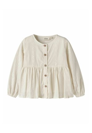 Blouse blanche à manches longues boutonnée, col rond, taille froncée et délicate broderie en dentelle sur le devant et les manches.