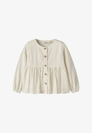 Blouse blanche à manches longues boutonnée, col rond, taille froncée et délicate broderie en dentelle sur le devant et les manches.
